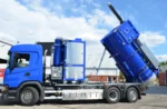 Sininen Disab Centurion P10 -suurtehoimuri, jonka säiliö on nostettu tyhjennysasentoon. Ajoneuvossa näkyy alipaineyksikkö, ohjauspaneeli ja hydraulinen kippi. Kuvattu teollisuusalueella kirkkaassa säässä.