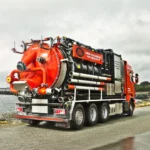 Disab Centurion P20 -suurtehoimuri oranssilla kolmiakselisella alustalla, varustettuna alipainejärjestelmällä ja säiliörakenteella. Kuvattu merenrannan läheisyydessä pilvisessä säässä.