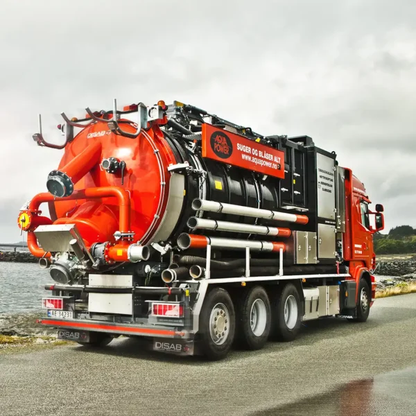 Disab Centurion P20 -suurtehoimuri oranssilla kolmiakselisella alustalla, varustettuna alipainejärjestelmällä ja säiliörakenteella. Kuvattu merenrannan läheisyydessä pilvisessä säässä.