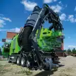 Disab Futurion Q10 Multiflex suurtehoimuri vihreällä kuorma-autoalustalla - nostovarsi pystyssä ja musta spiraaliletkusto rakennustyömaalla.