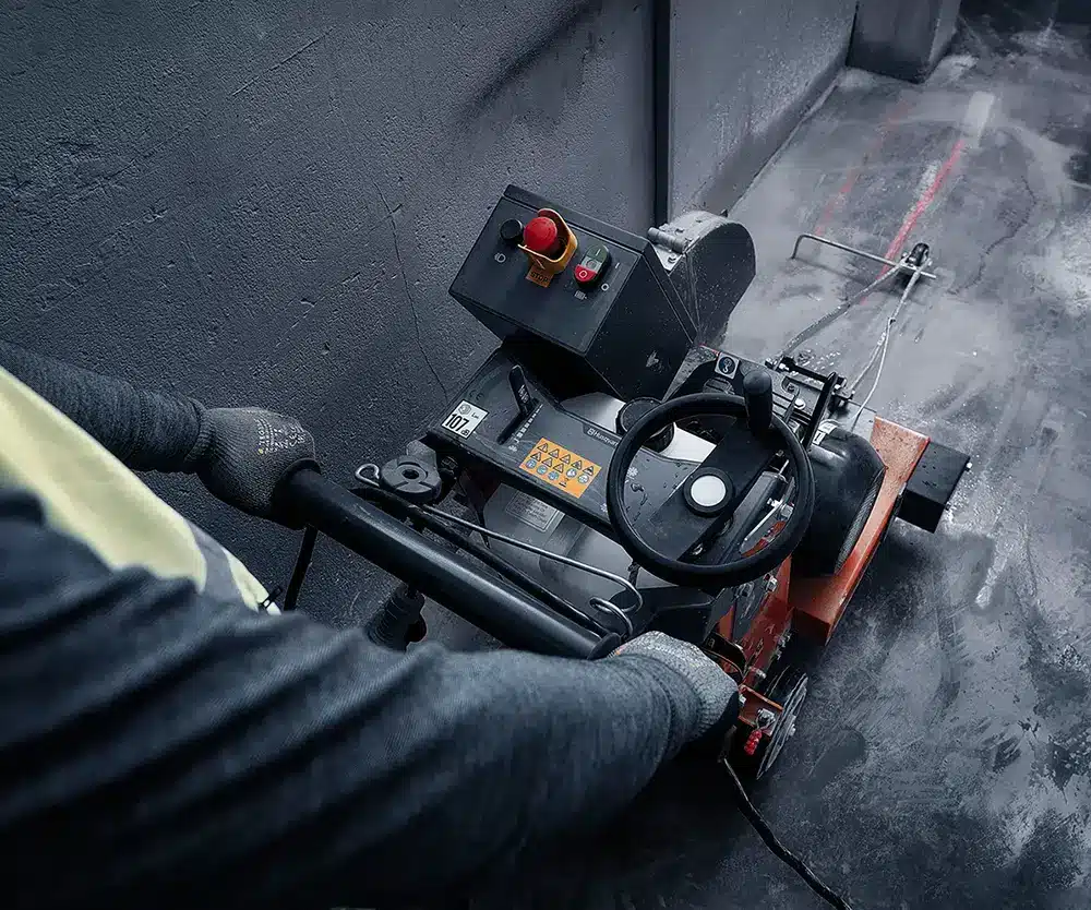 Husqvarna FS 600 E sähkölattiasaha käytössä - yläkuva käyttäjän ohjatessa lattiasahaa betonityömaalla.