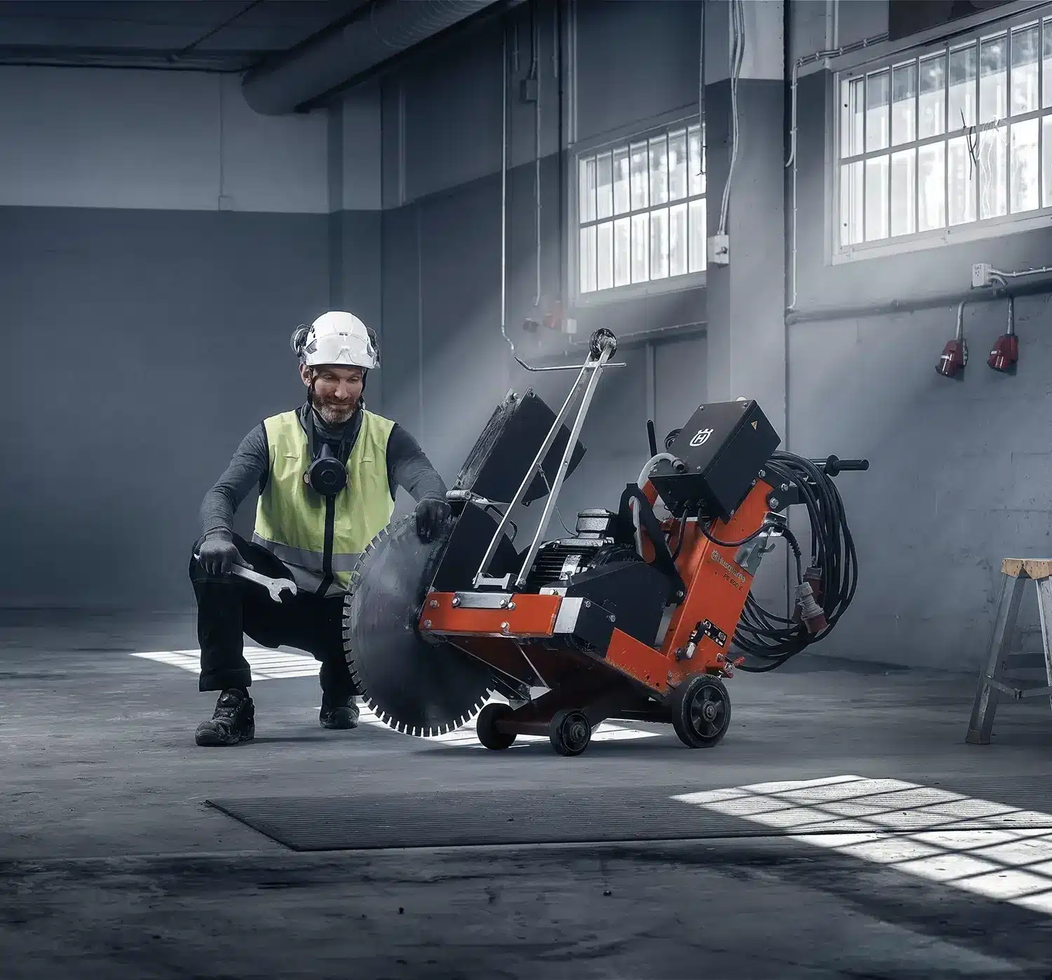 Husqvarna FS 600 E sähkölattiasaha - rakennusalan ammattilainen poseeraa lattiasahan kanssa sisätyömaalla.