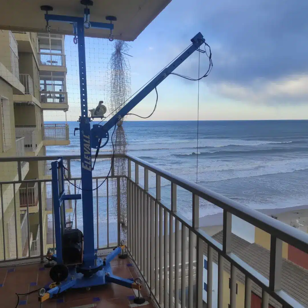 Parvekkeelle asennettu Elevall 400 kerrosnosturi; masto ja kääntyvä puomi ulottuvat kaiteen yli julkisivutyöhön.