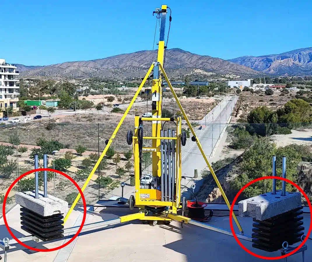 Elevall 400 -kerrosnosturin vastapainot kattoasennuksessa; betonilaatat ja teräspainot tukevat nosturin vakautta korkealla työskentelyssä.