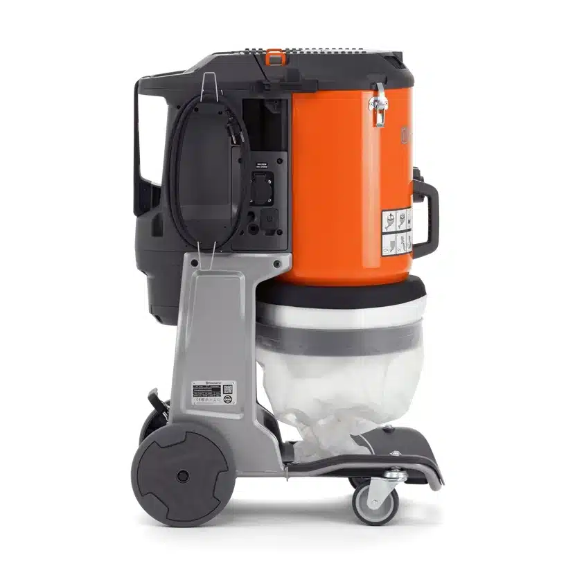 Husqvarna DE 110 SH -pölynerotinimuri sivusta kuvattuna, oranssi lieriömäinen runko harmaalla teräsrungolla, valkoinen läpikuultava pölysäkki alhaalla, kaksi suurta takapyörää ja kaksi pientä kääntyvää etupyörää, virtajohto näkyvissä sivupaneelissa.