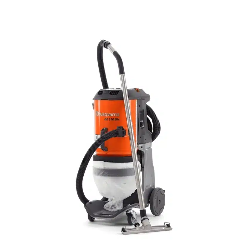 Husqvarna DE 110 SH -pölynerotinimuri varusteineen etuviistosta kuvattuna, oranssi lieriömäinen runko harmaalla teräsrungolla, valkoinen läpikuultava pölysäkki, musta joustava imuletku, metallinen teleskooppivarsi ja lattiasuutin.