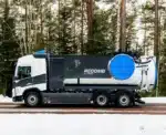 Valkoinen ja tummanharmaa ReComb-imupaineauto talvisella tiellä metsän keskellä, säiliön päässä suuri sininen pyöreä kansi.
