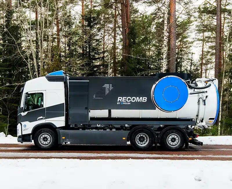 Valkoinen ja tummanharmaa ReComb-imupaineauto talvisella tiellä metsän keskellä, säiliön päässä suuri sininen pyöreä kansi.